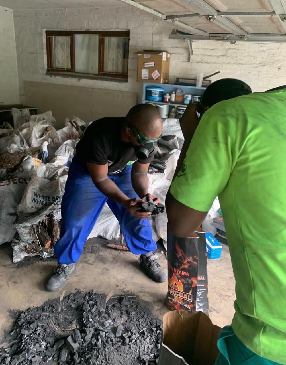 Two workers bagging charcoal