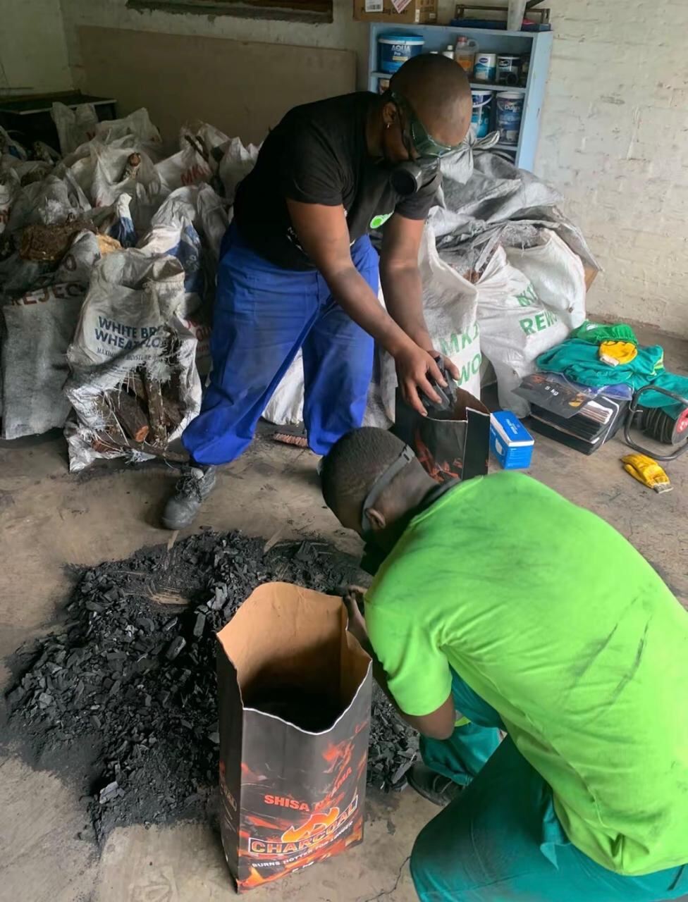 Worker sorting loose charcoal into a bag